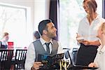 Handsome businessman ordering food from waitress in a restaurant