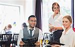 Business people and waitress smiling at camera in restaurant