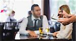 Waitress writing an order in front of two business people talking