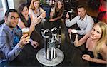 Attractive friends raising glasses up smiling at camera in a restaurant