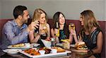 Happy friends sitting together having dinner in a restaurant