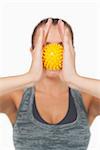 Young woman holding yellow massage ball between hands in front of her face