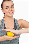 Attractive woman holding yellow massage ball between her hands smiling at camera