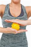 Close up of young woman holding yellow massage ball between her hands on white screen