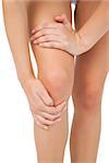 Close up of slim woman touching her injured knee on white background