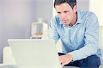 Content casual man looking at laptop in bright living room