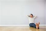 Casual pensive man leaning against wall with crossed arms in bright room