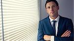 Content handsome businessman standing with crossed arms in dark room