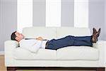 Calm handsome businessman lying on couch after work at home