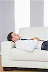 Peaceful handsome businessman lying on couch after work at home