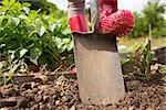 Woman wearing rubber boots working in the garden using a shovel