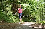 Pretty young woman jogging in a forest on a sunny day