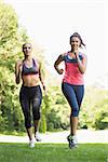 Two fit brunette women jogging towards camera in a forest