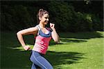 Fit woman running in the sunshine outside in a park