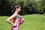 Fit woman running in the sunshine and smiling outside in a park