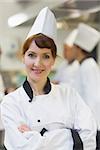 Female chef posing proudly in a kitchen with crossed arms