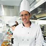 Handsome male chef posing in the kitchen smiling at the camera