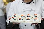 Chef presenting plate of meringues in commercial kitchen