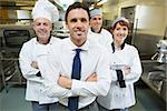 Restaurant manager posing in front of team of chefs smiling at camera