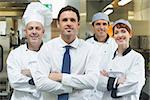 Restaurant manager standing in front of team of chefs smiling at camera