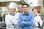 Young manager posing with some chefs in a kitchen