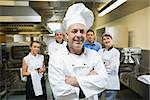 Head chef posing with team behind him in a professional kitchen