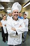 Head chef posing with his team behind him in restaurant kitchen
