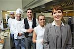 Nice female manager posing with the staff in a professional kitchen