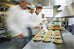 Four chefs working in a modern kitchen preparing soups