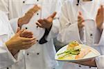 Chefs applauding a salmon dish in commercial kitchen