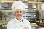 Mature head chef posing with crossed arms standing in a professional kitchen