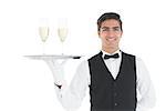 Smiling attractive waiter holding a tray with champagne glasses on it smiling at camera