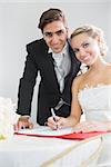 Portrait of pretty young couple signing wedding contract smiling at camera