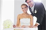 Attractive couple signing wedding register smiling at camera