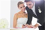 Beautiful bride watching her handsome husband signing wedding contract