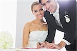 Happy bridegroom signing wedding contract smiling at camera