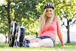 Casual cheerful blonde wearing roller blades in a park