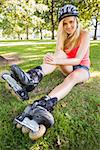 Casual gorgeous blonde wearing roller blades and helmet in a park