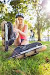 Casual pretty blonde wearing roller blades and helmet in a park