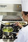 Young chef stirring sauce in professional kitchen