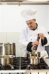 Concentrating head chef using pepper mill in professional kitchen