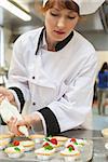 Pretty concentrating head chef preparing dessert in professional kitchen