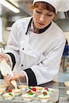 Pretty concentrated head chef preparing dessert in professional kitchen