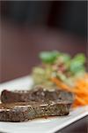 Close up of meat garnished with salad on white plate