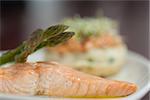 Close up of salmon dish with asparagus on white plate