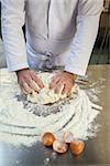 Close up of baker kneading dough in professional kitchen