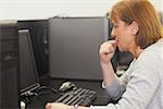 Unsure female mature student working on computer in computer class