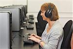 Female mature student working on computer while listening to music