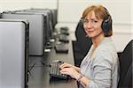 Portrait of female mature student working on computer while listening to music