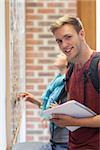 Cheerful student searching something on notice board in school